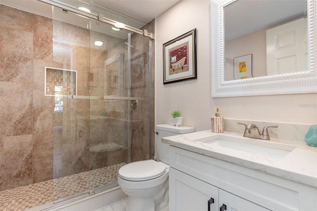 bathroom with vanity, toilet, and a shower with door