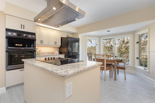 kitchen featuring white cabinetry, island exhaust hood, a center island, and black appliances