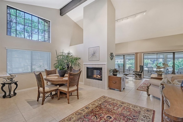 tiled dining room with beamed ceiling, high vaulted ceiling, and a tiled fireplace