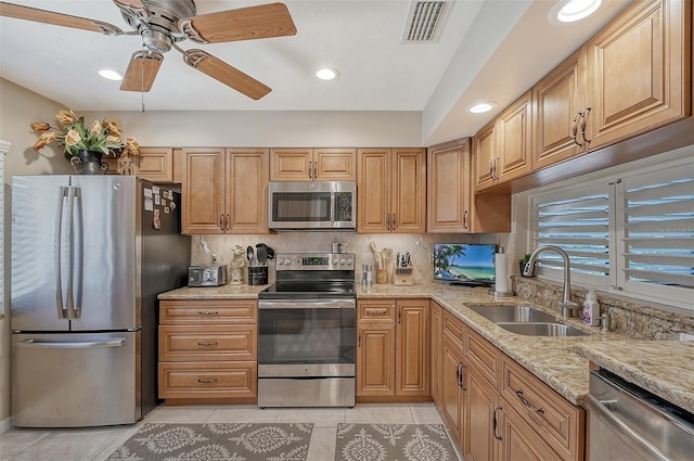 kitchen with light stone countertops, ceiling fan, stainless steel appliances, sink, and light tile floors