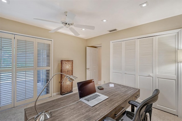 carpeted office space featuring ceiling fan