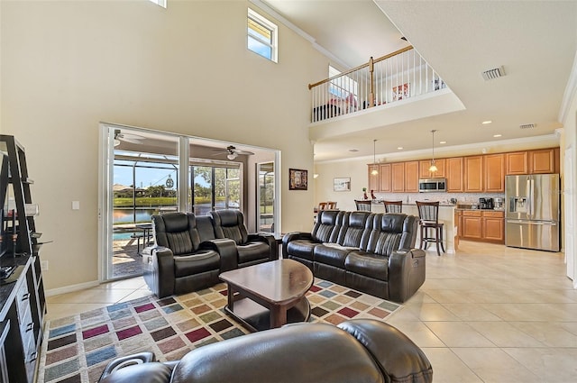 tiled living room featuring crown molding, ceiling fan, and a towering ceiling