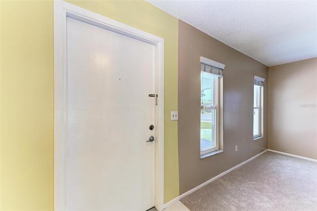 entryway featuring light colored carpet and a textured ceiling