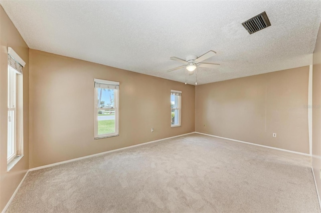 unfurnished room featuring light colored carpet, ceiling fan, and a textured ceiling