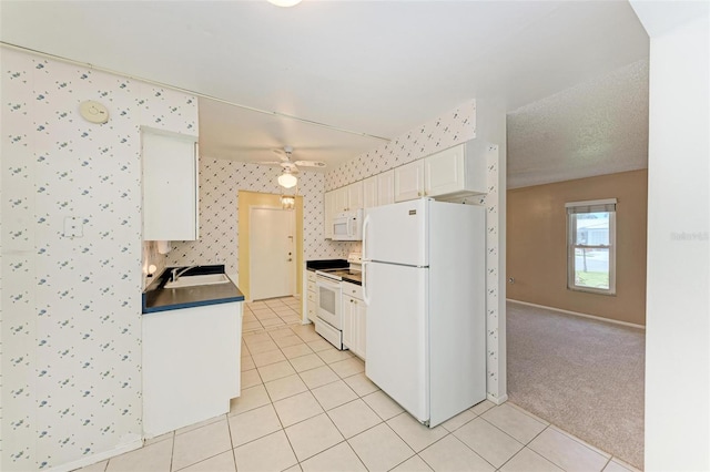 kitchen with white appliances, ceiling fan, light carpet, white cabinetry, and sink