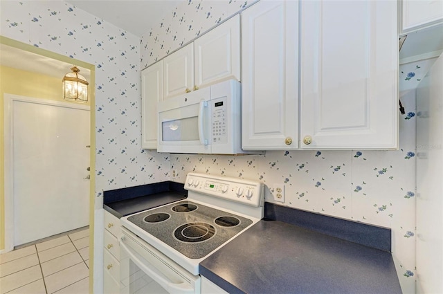 kitchen with white appliances, light tile flooring, and white cabinetry