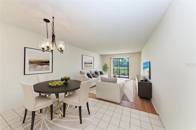 dining area featuring light tile patterned floors, baseboards, a textured ceiling, and an inviting chandelier