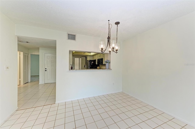 spare room with a chandelier, a textured ceiling, and light tile floors