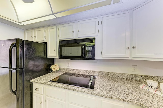 kitchen with white cabinetry, black appliances, and light stone countertops