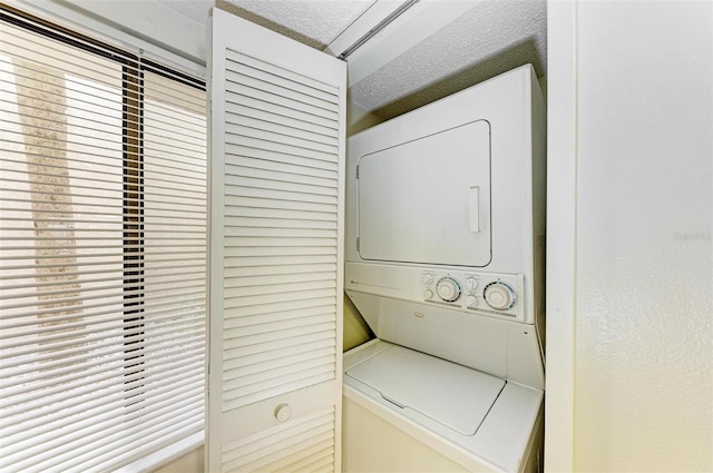 laundry area featuring a textured ceiling and stacked washing maching and dryer