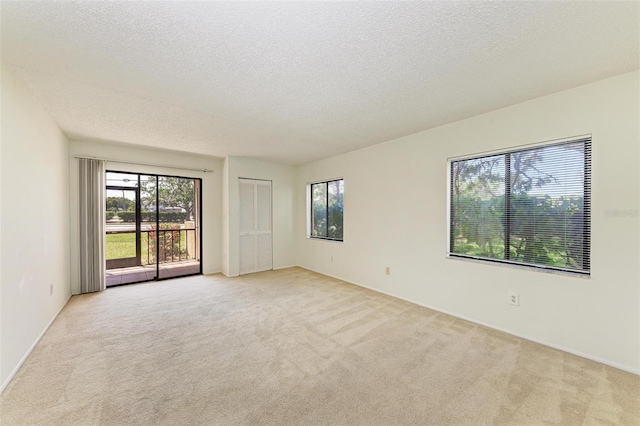 unfurnished room with light carpet and a textured ceiling