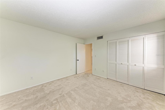 unfurnished bedroom with light carpet, a closet, and a textured ceiling