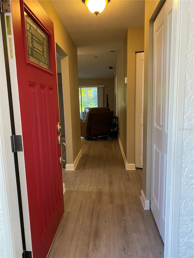 hall featuring light hardwood / wood-style floors and a textured ceiling