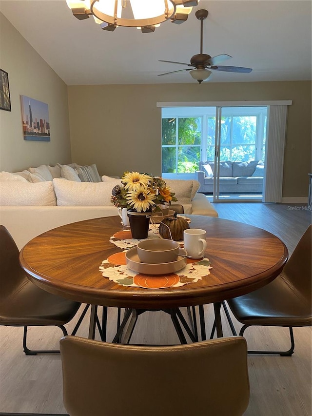 dining area featuring vaulted ceiling, ceiling fan with notable chandelier, and light hardwood / wood-style floors