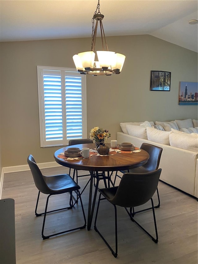 dining area featuring lofted ceiling, light hardwood / wood-style flooring, and a notable chandelier