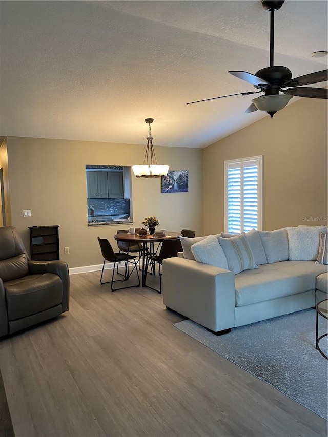 living room with lofted ceiling, ceiling fan, hardwood / wood-style flooring, and a textured ceiling