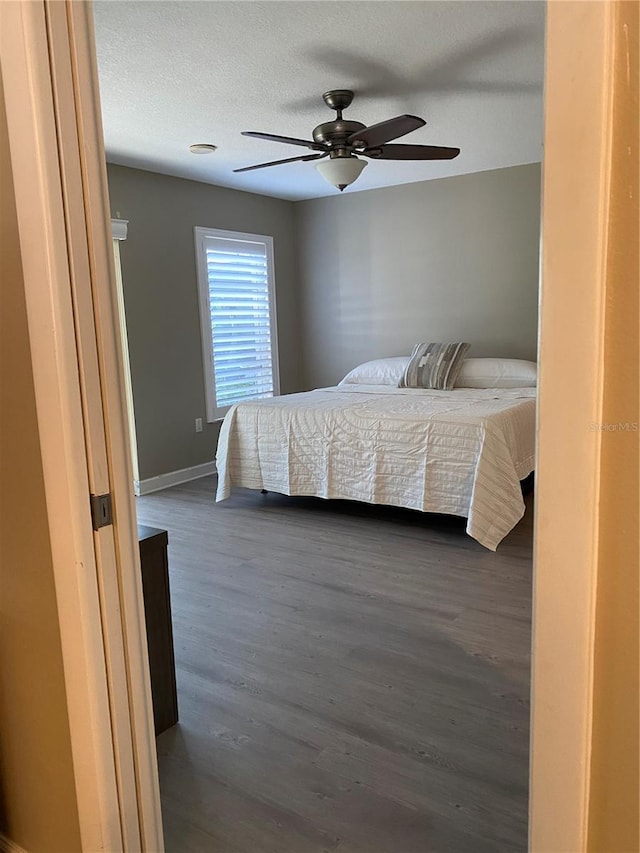 bedroom featuring a textured ceiling, dark wood-type flooring, and ceiling fan