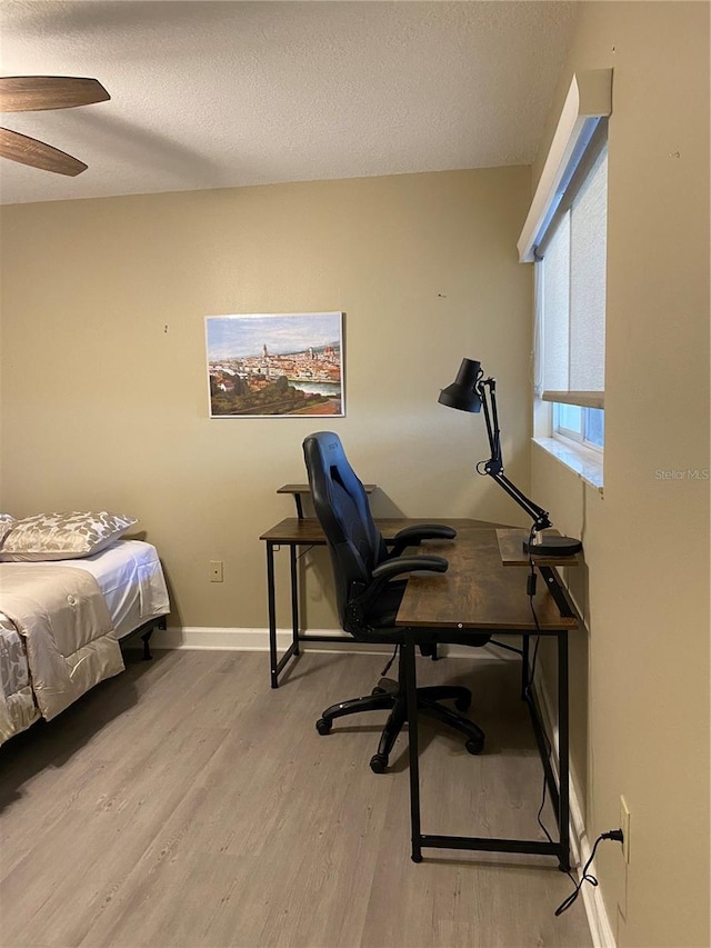 bedroom with a textured ceiling, ceiling fan, and light hardwood / wood-style flooring