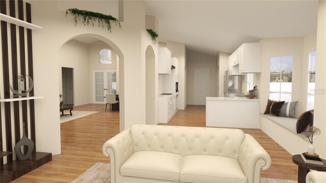 living room featuring french doors, high vaulted ceiling, sink, and light wood-type flooring