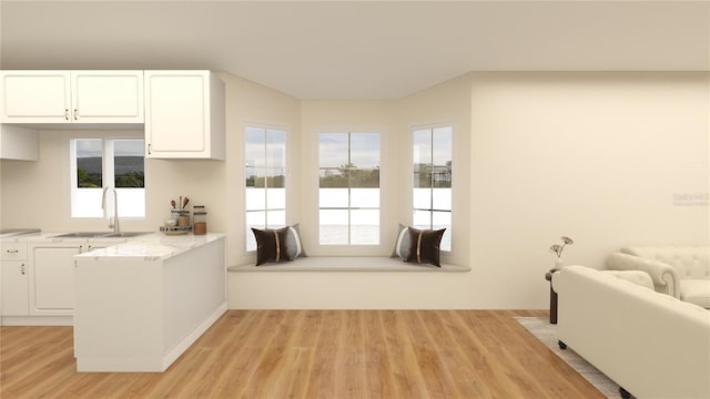 kitchen with light stone countertops, sink, white cabinets, and light hardwood / wood-style floors