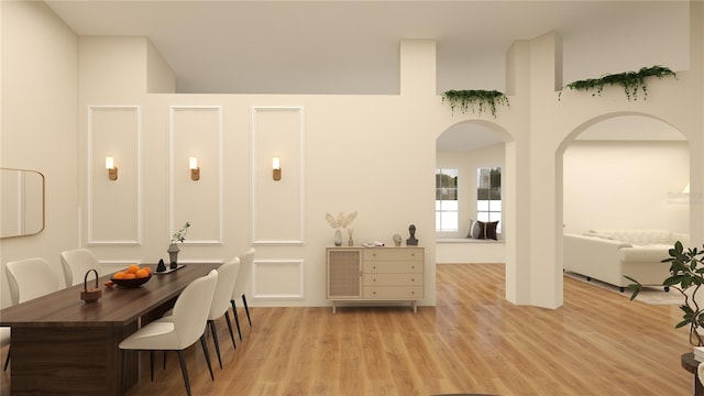 dining room with light wood-style flooring and arched walkways