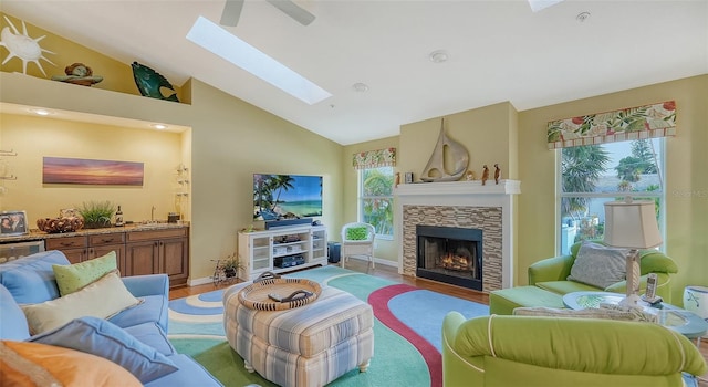 living room featuring light hardwood / wood-style flooring, vaulted ceiling with skylight, and a fireplace