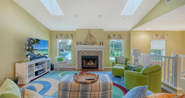 living room with hardwood / wood-style floors, lofted ceiling with skylight, and a stone fireplace