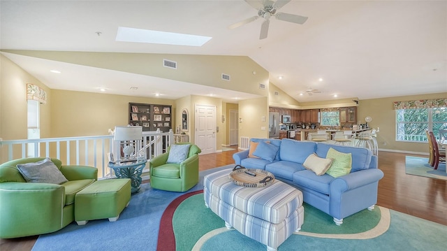 living room featuring a skylight, high vaulted ceiling, ceiling fan, and hardwood / wood-style flooring