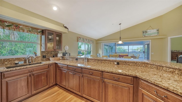 kitchen with lofted ceiling, sink, light hardwood / wood-style floors, and light stone counters