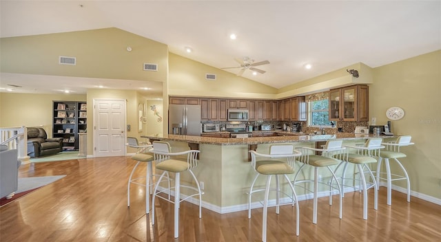 kitchen with stone countertops, stainless steel appliances, backsplash, and a kitchen bar