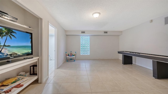 interior space featuring a textured ceiling, light tile floors, and a water view