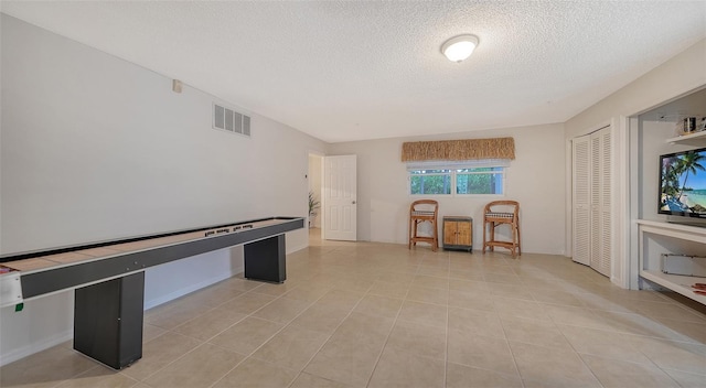 playroom featuring light tile floors and a textured ceiling