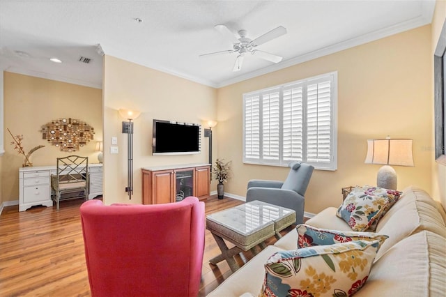 living room featuring crown molding, ceiling fan, and light hardwood / wood-style flooring