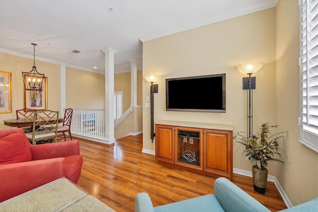 living room featuring ornamental molding, a wealth of natural light, light hardwood / wood-style flooring, and ornate columns