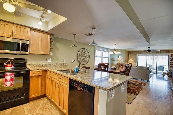 kitchen featuring hanging light fixtures, ceiling fan with notable chandelier, black appliances, kitchen peninsula, and sink