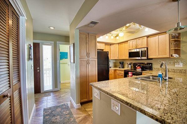 kitchen featuring light stone counters, ceiling fan, light tile floors, and black appliances