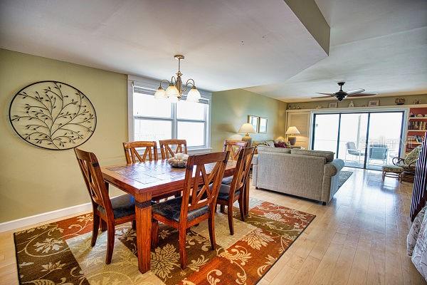 dining space with ceiling fan with notable chandelier and light hardwood / wood-style floors