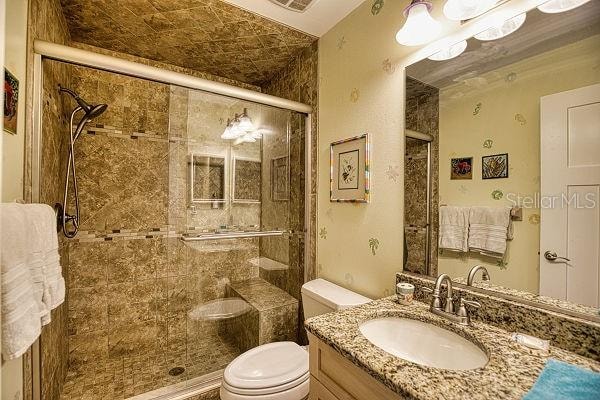 bathroom with vanity with extensive cabinet space, an enclosed shower, and toilet