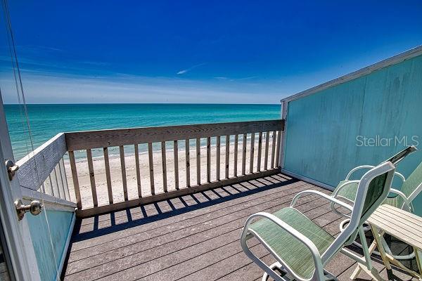 wooden terrace with a water view and a view of the beach