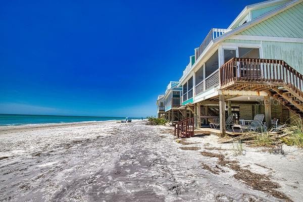 view of side of property featuring a deck with water view, a view of the beach, and a sunroom