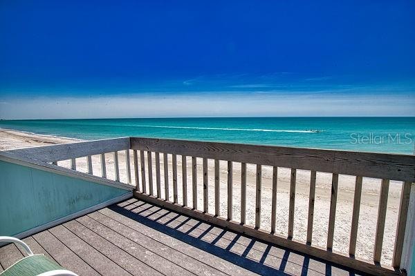 wooden deck featuring a water view and a view of the beach