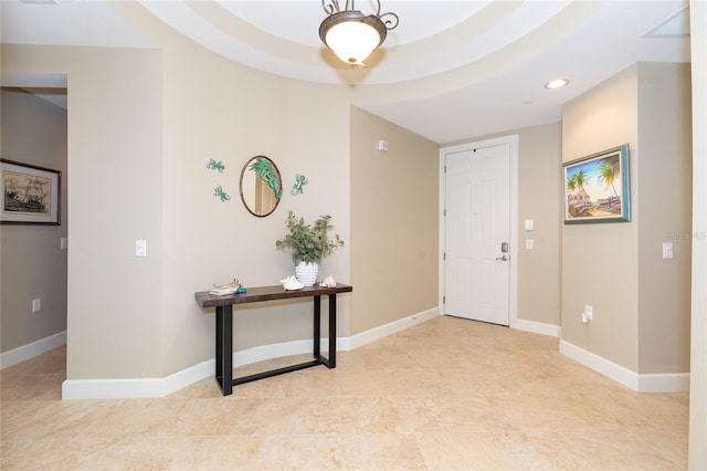 foyer featuring light tile floors and a tray ceiling