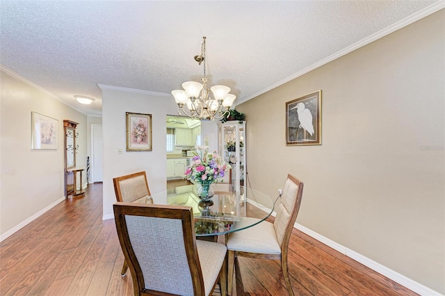 dining area featuring an inviting chandelier, crown molding, a textured ceiling, and hardwood / wood-style flooring