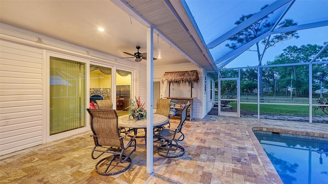 patio terrace at dusk with glass enclosure and ceiling fan