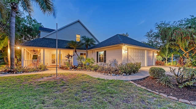 rear view of property with a yard, a garage, and a porch