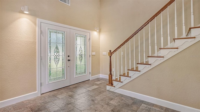 foyer entrance featuring french doors, light tile floors, and a wealth of natural light