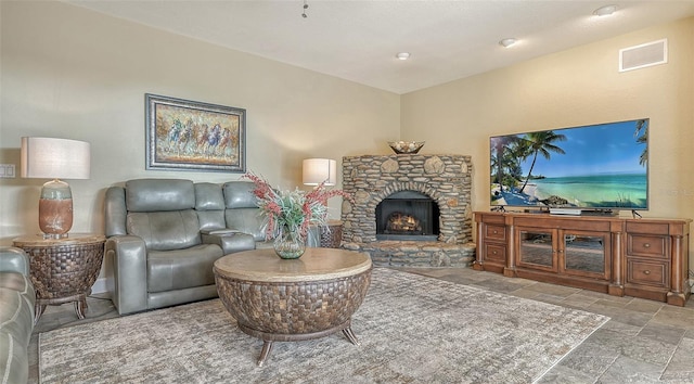 living room with light tile floors and a stone fireplace