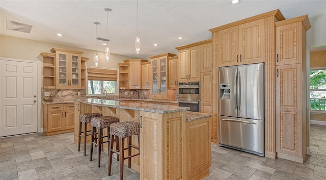 kitchen featuring a wealth of natural light, appliances with stainless steel finishes, hanging light fixtures, and backsplash