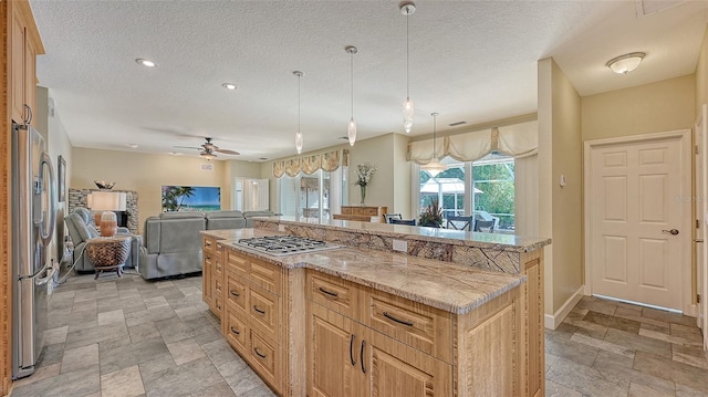 kitchen featuring a center island, hanging light fixtures, stainless steel appliances, light tile floors, and ceiling fan