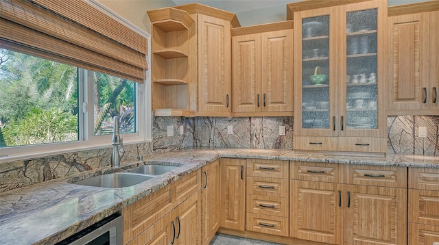 kitchen with tasteful backsplash, light brown cabinets, sink, and light stone countertops